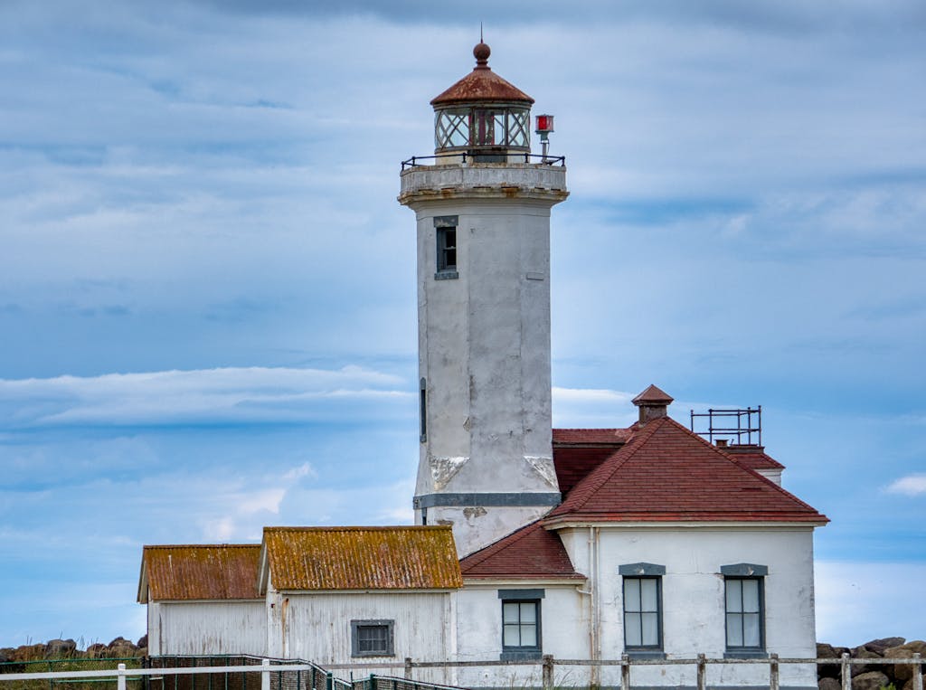 A picturesque view of the historic Point Wilson Lighthouse in Port Townsend, WA under a vivid sky.