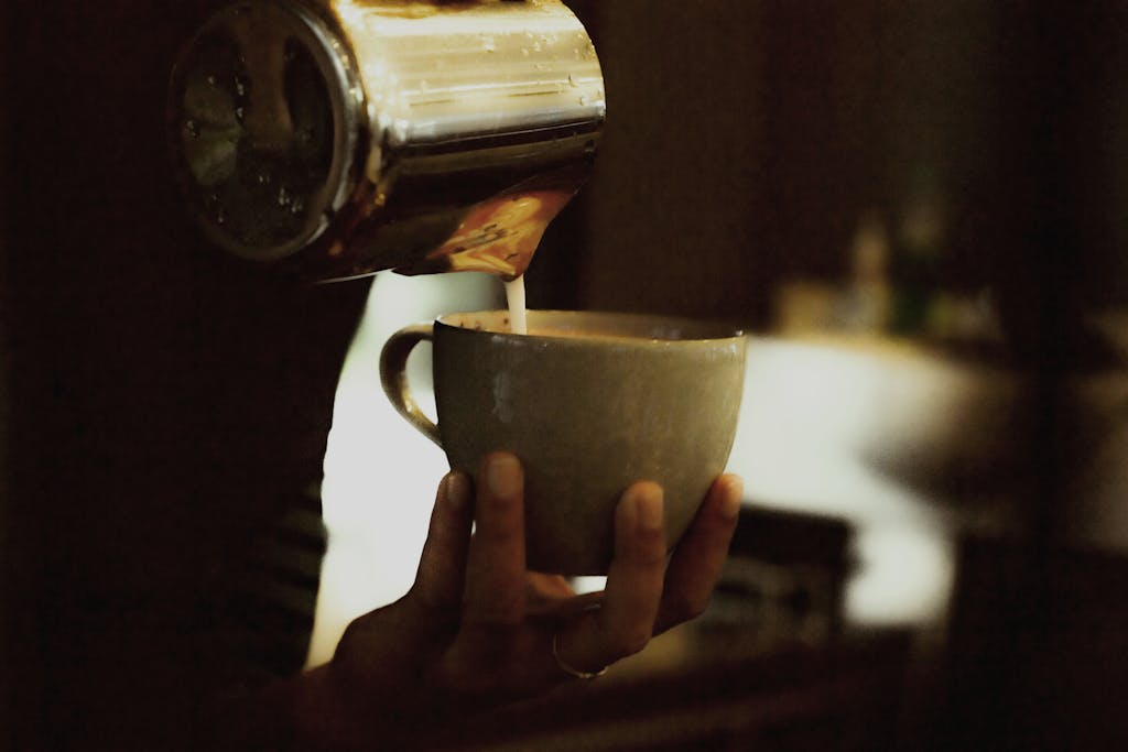 Close-up of latte art being poured into a ceramic cup in a cozy café ambiance. Perfect for coffee lovers.